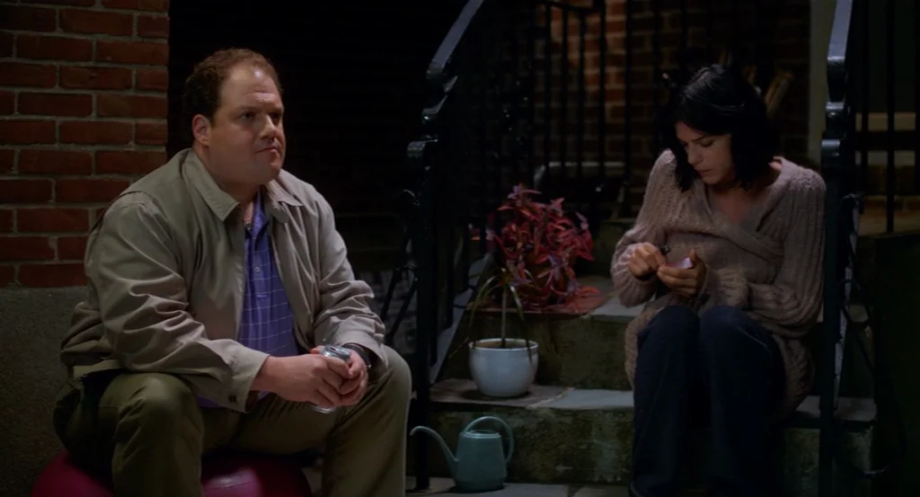 Dark Horse (2011) movie still: medium — A brick exterior wall features stone steps leading up to an entrance. A man and a woman sit on the stairs…