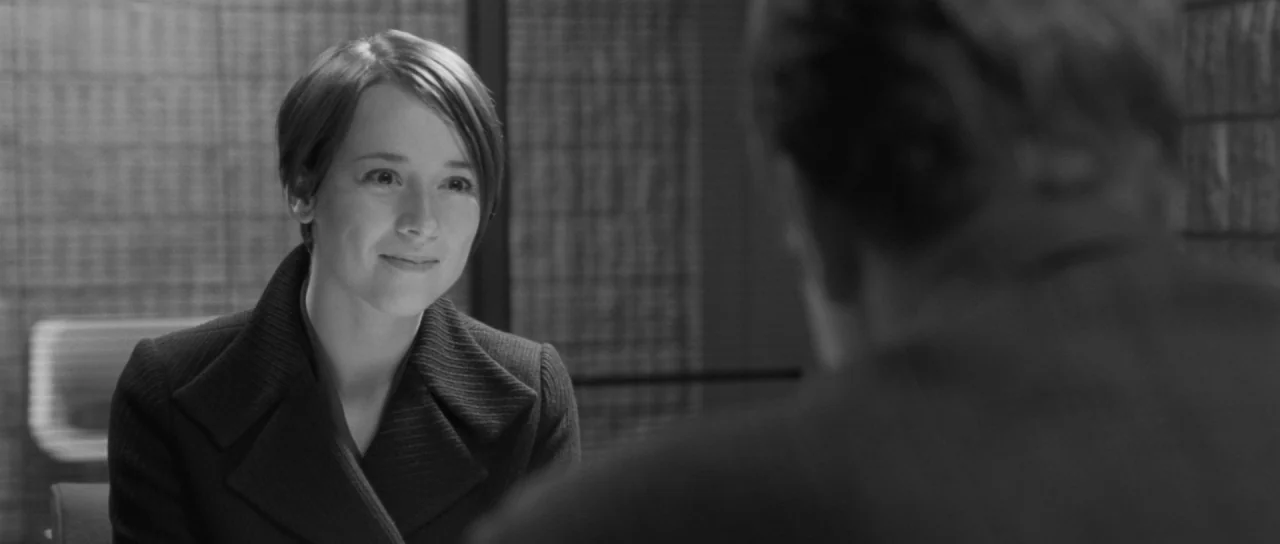Polytechnique (2009) movie still: medium — An office interior features a modern desk and blurred background slatted window blinds. A woman in a dark…