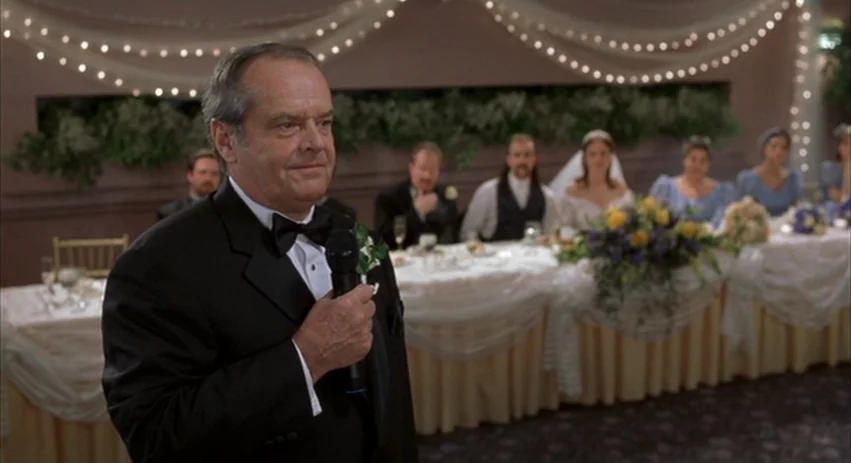 About Schmidt movie still: medium — A banquet hall decorated with white fabric swags and small fairy lights at night. A middle-aged man in a tuxedo…