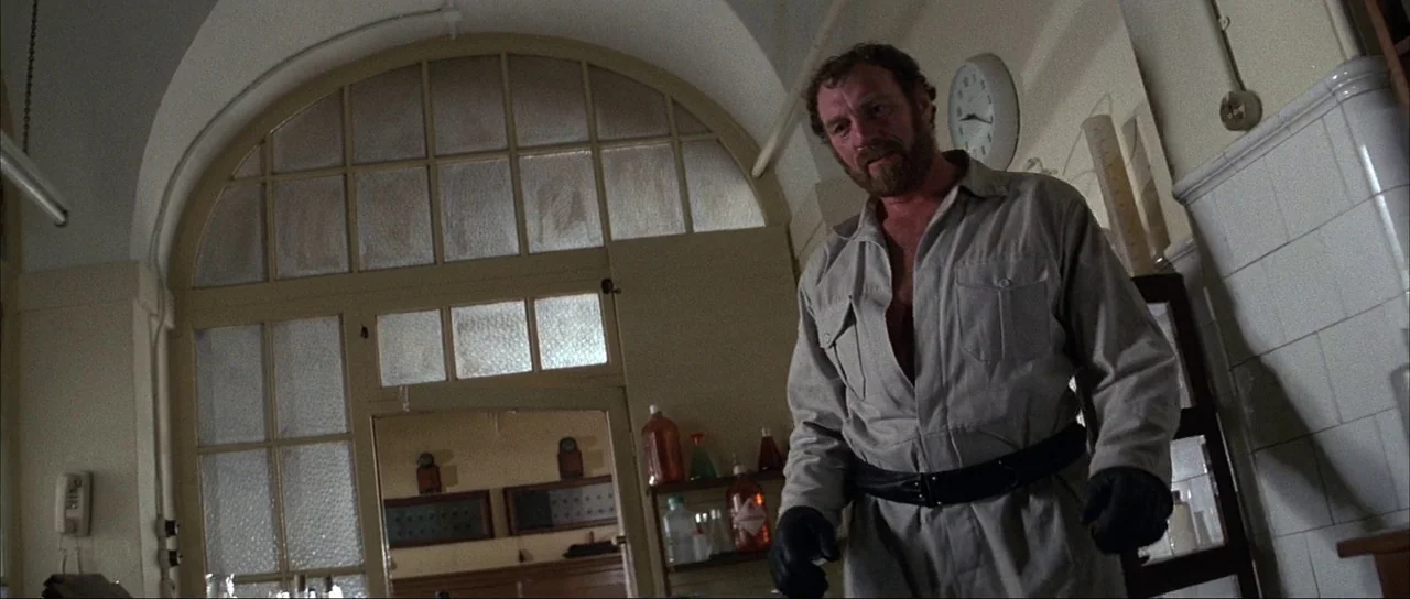 Never Say Never Again (1983) movie still: medium — A laboratory features white tiled walls and a large arched glass partitioned window. A bearded…