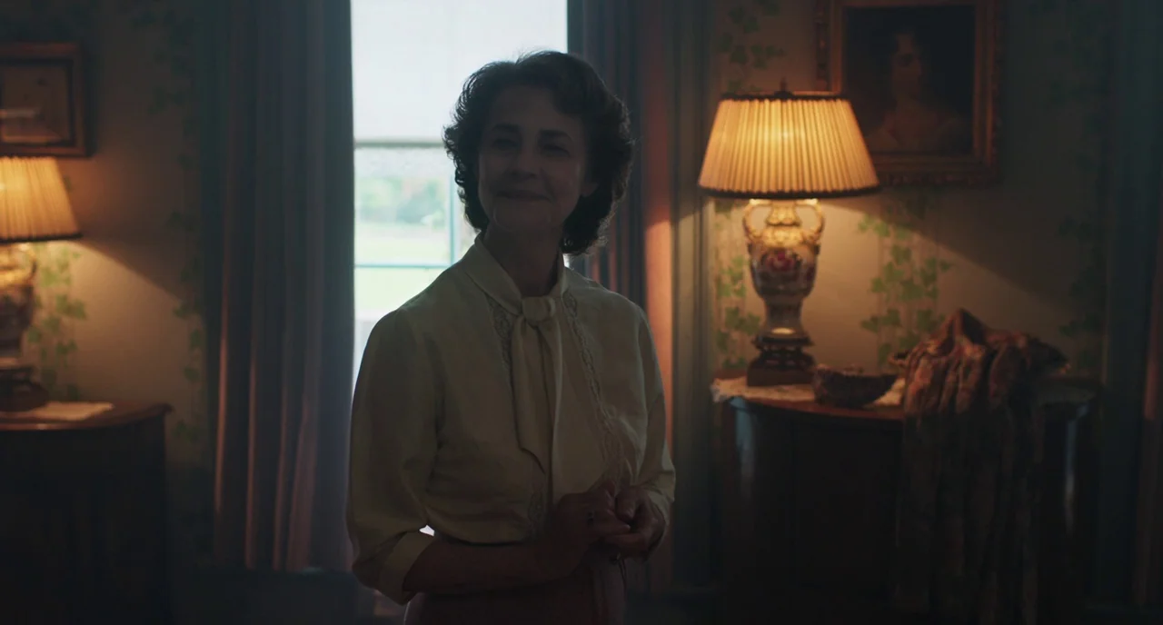 The Little Stranger (2018) movie still: medium — A dimly lit room with wallpaper featuring a leaf pattern and antique furniture. A mature woman with…