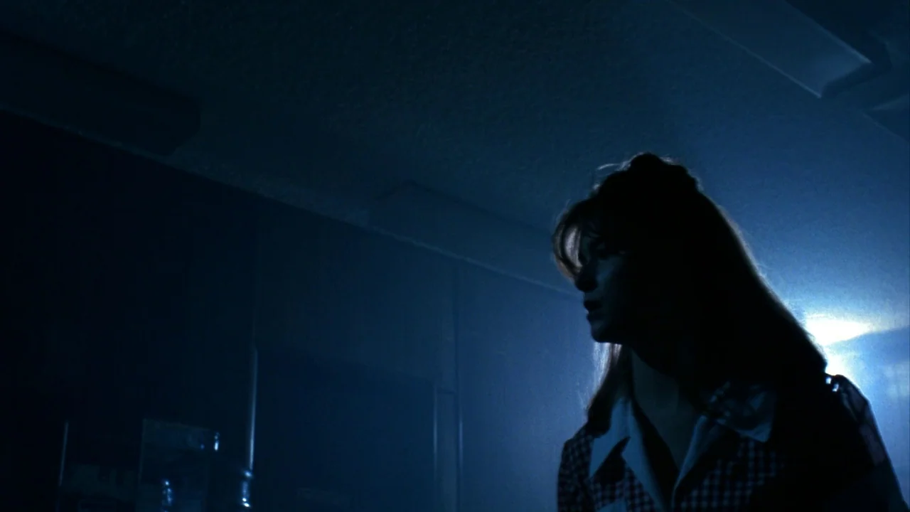 Jason Goes To Hell (1993) movie still: medium — An interior space is cast in deep shadow with cool blue light. A woman stands in profile,…