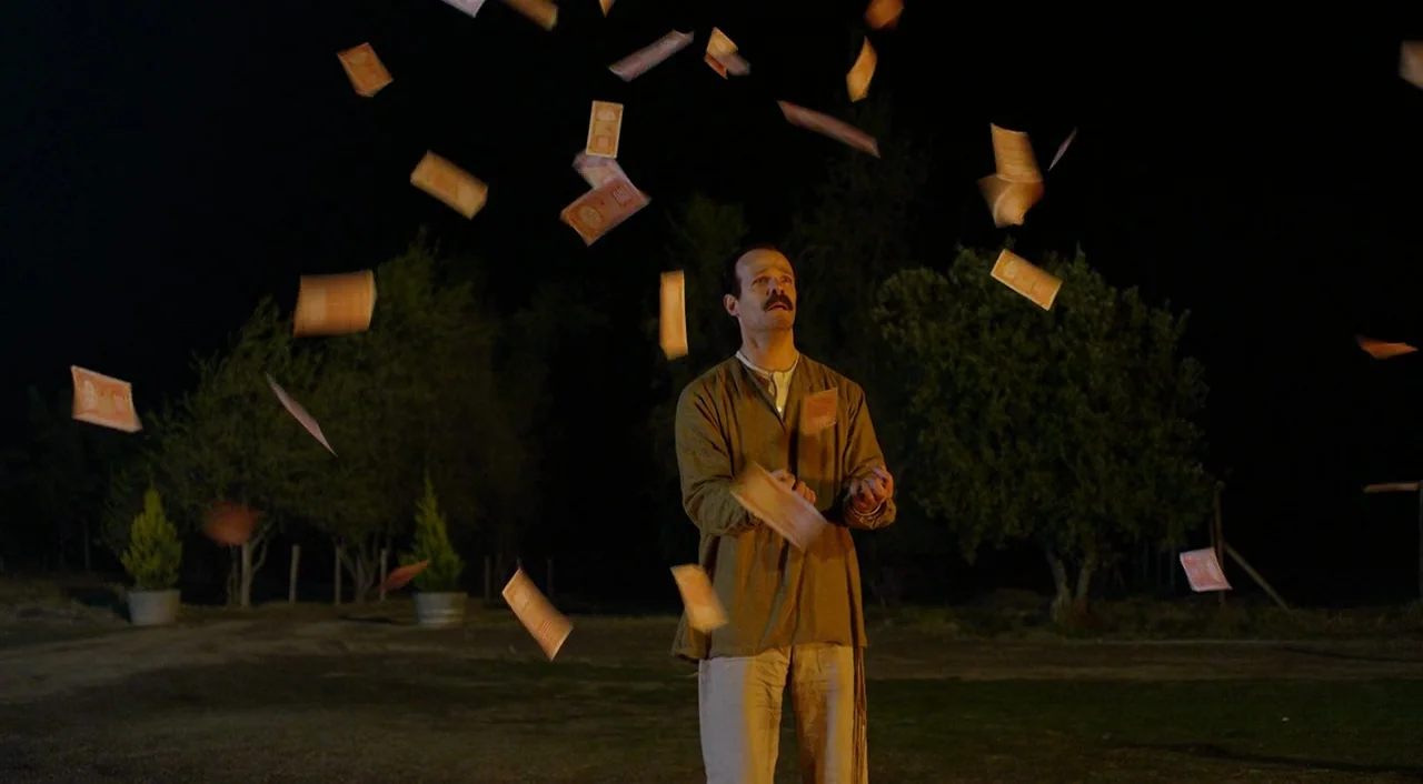 Dance of Reality (2013) movie still: fullbody — A dark outdoor setting at night features a grassy area with sparse trees. A man stands alone looking…