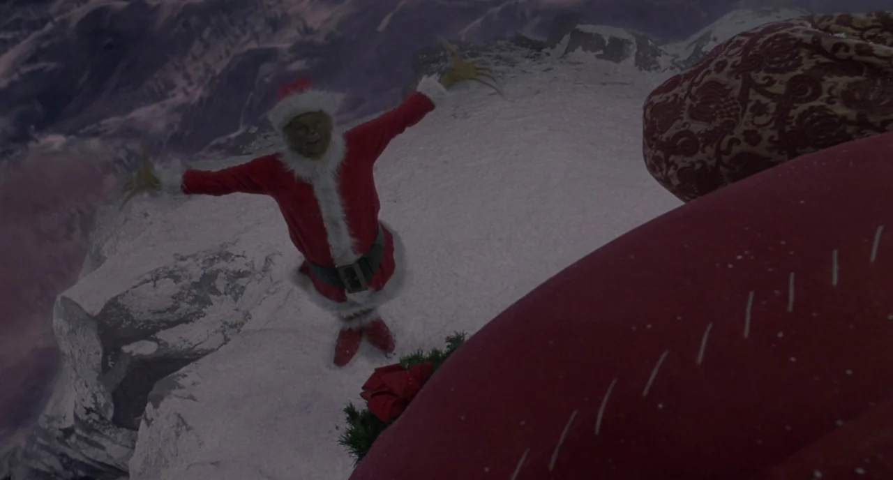 How The Grinch Stole Christmas (2000) movie still: wide — A dark, snow-covered cliffside edge looms above a distant, blurry mountain landscape. The…