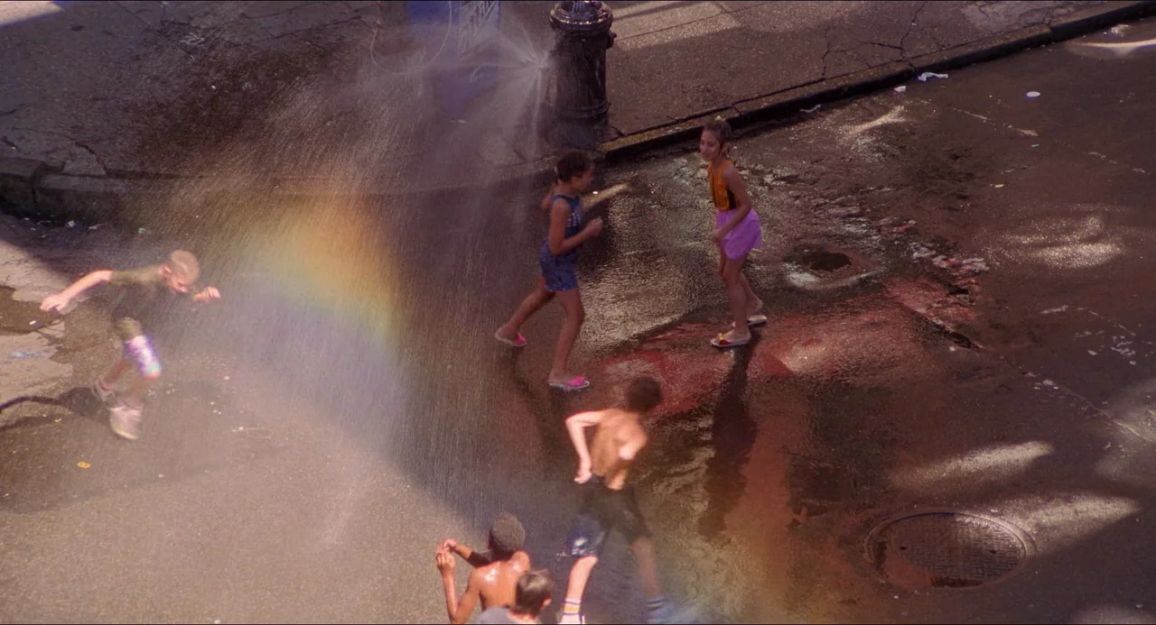 The Prince of Tides (1991) movie still: wide — A group of children play in the cooling mist of an open fire hydrant. Water sprays across the wet…