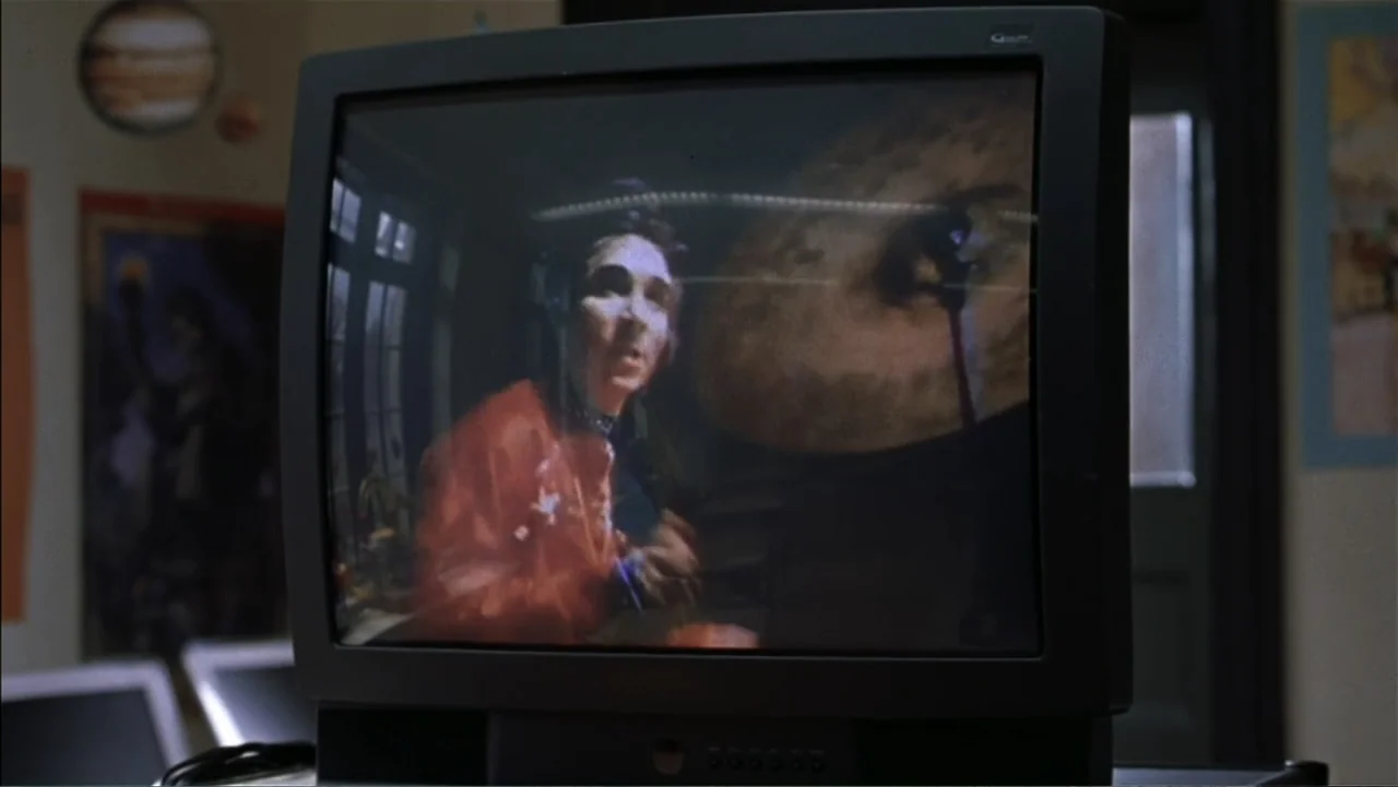 School of Rock (2003) movie still: medium — A dark television monitor sits in a classroom displaying a video of a person. The screen shows a person…