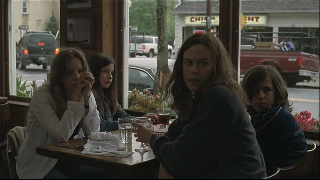 Margot At The Wedding (2007) movie still: medium — A group of four people sits at a wooden table inside a roadside eatery. They are positioned in…
