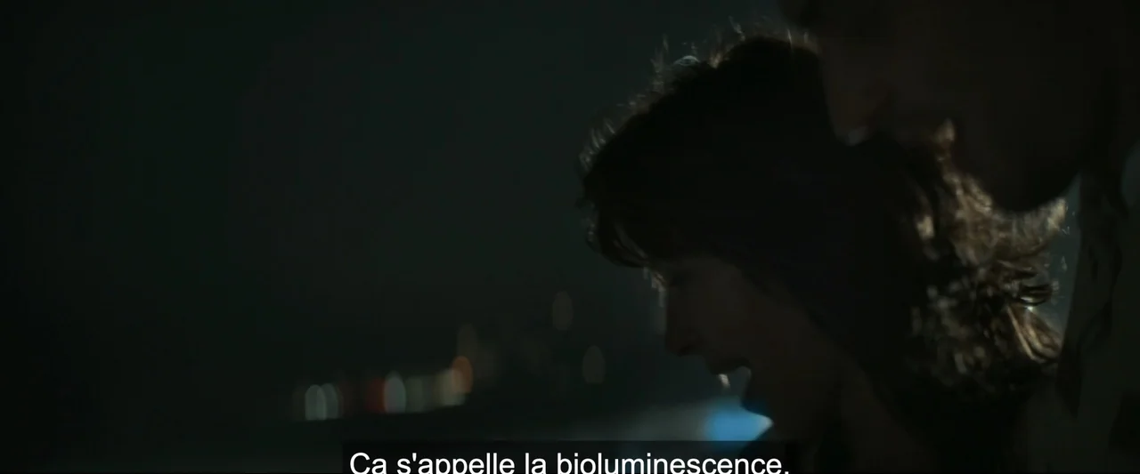 I Love America (2022) movie still: closeup — A nighttime outdoor setting with blurred light points in the distant background. Two people stand close…