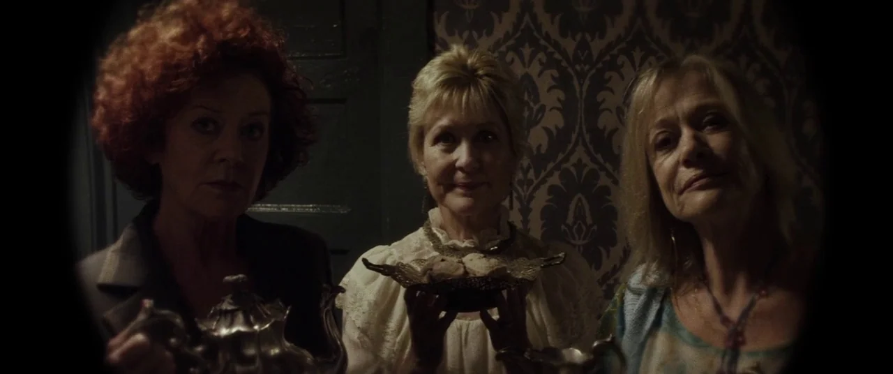 Lords Of Salem (2013) movie still: medium — Three older women stand side-by-side inside a narrow space with dark patterned wallpaper. They hold a…