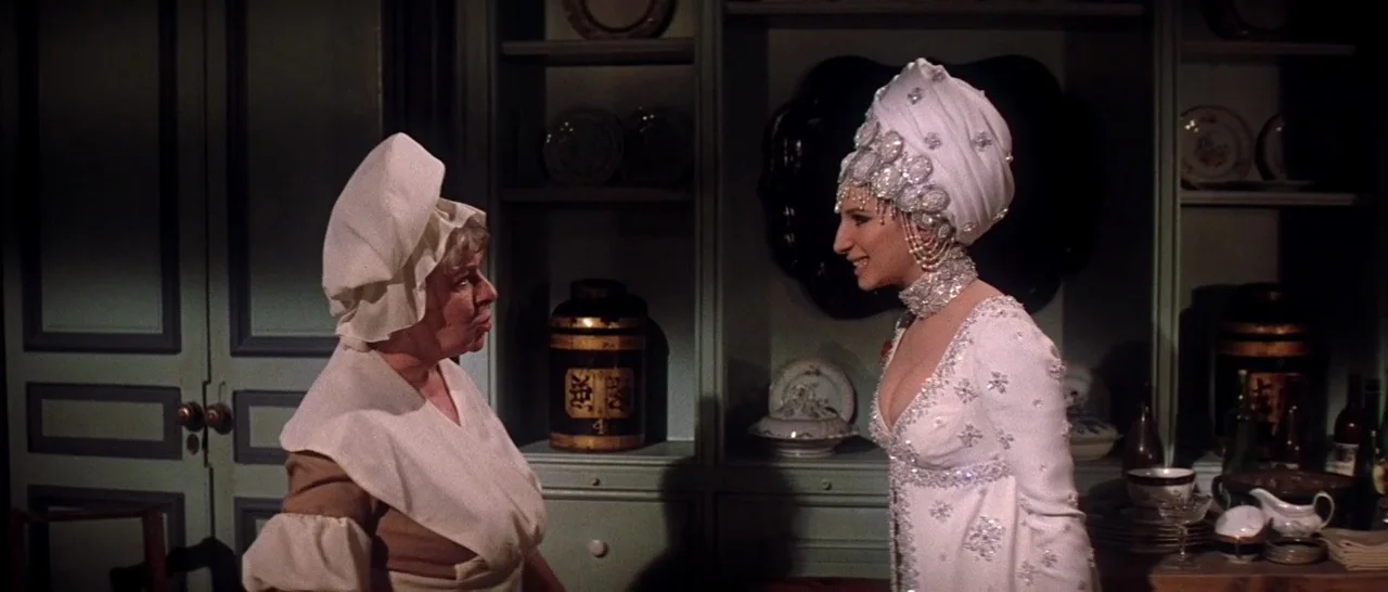 On A Clear Day You Can See Forever (1970) movie still: medium — A pantry features sage green cabinets filled with decorative plates and containers.…