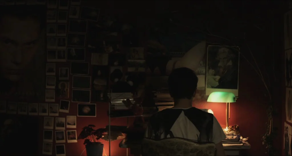 I Killed My Mother (J’ai tué ma mère) (2009) movie still: medium — A dimly lit room with walls covered in numerous polaroid photos and posters. A…