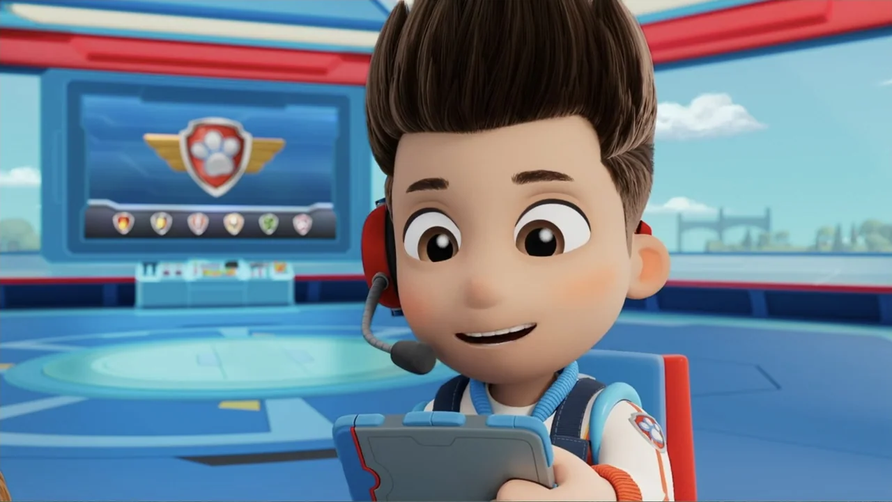 PAW Patrol: Air Rescue (2025) movie still: medium — A high-tech command center with blue floors and a digital display screen behind. A young boy in…