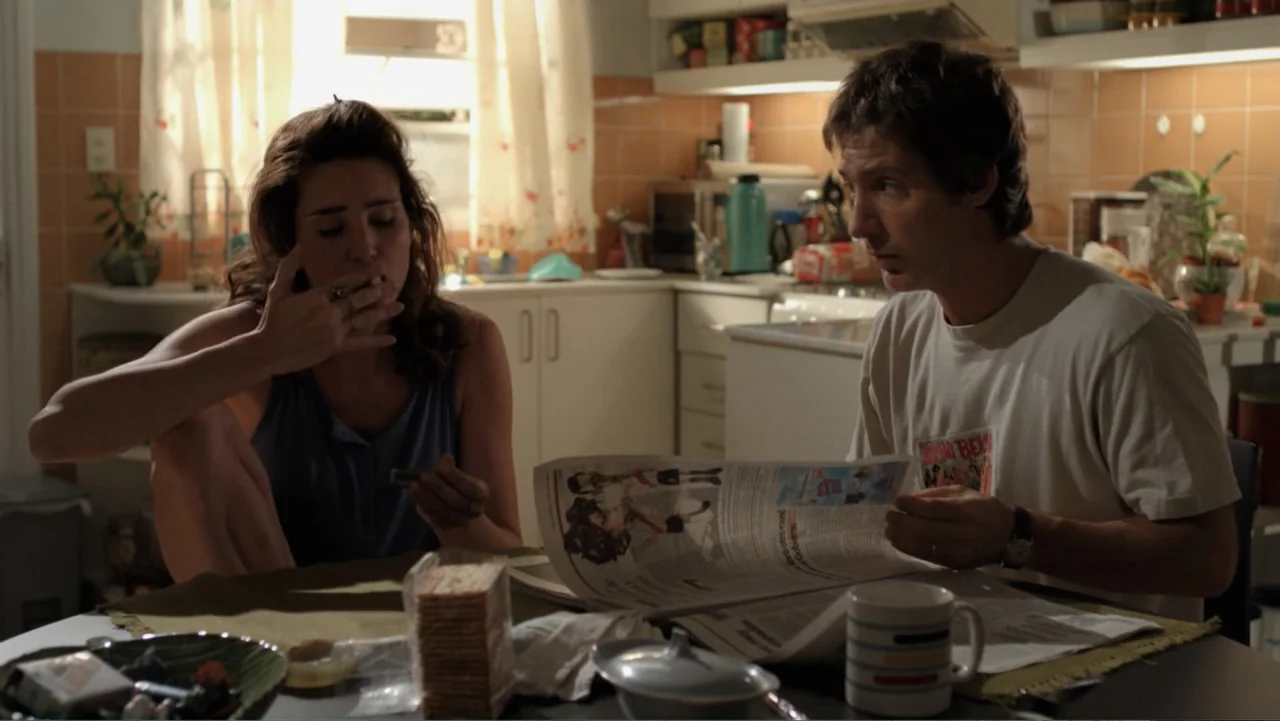 A Boyfriend for My Wife (2008) movie still: medium — A residential home interior features white cabinets and a table where two people sit. A woman…