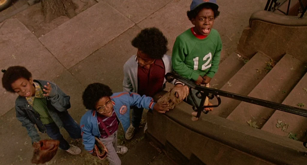 Mo’ Better Blues (1990) movie still: wide — Four children stand on a concrete sidewalk beside a set of stone steps. They are holding baseball gloves…