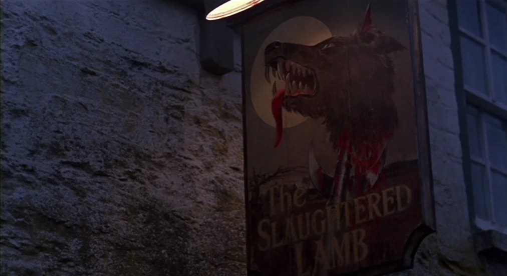 An American Werewolf in London (1981) movie still: closeup — A hanging wooden tavern sign features a painted wolf head with bloodied imagery. The…