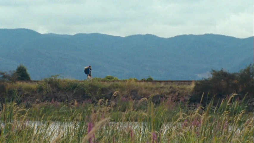 Wendy and Lucy (2008) movie still: wide — A remote railway track runs horizontally across the middle distance against rolling mountain ranges. A…