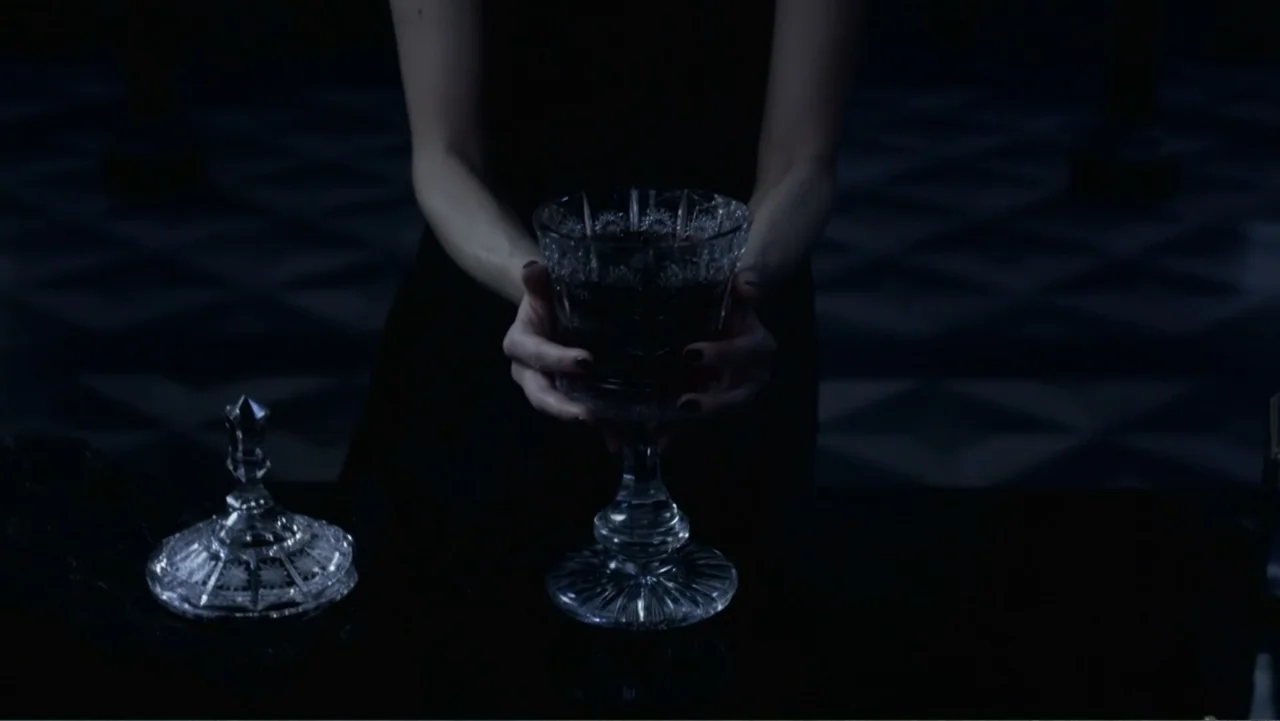 Underworld: Blood Wars (2016) movie still: medium — A dark, dimly lit interior space features a reflective black table surface. A woman in a black…
