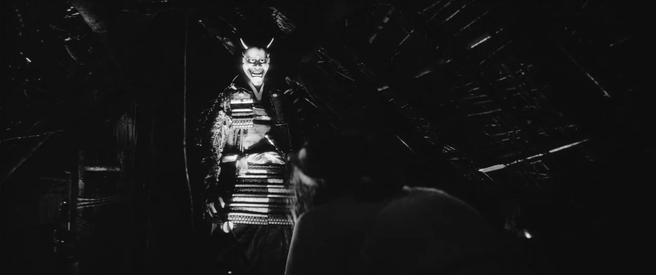 Onibaba (1964) movie still: fullbody — A dark, cramped interior of a traditional Japanese thatched hut with wooden supports. A figure in samurai…