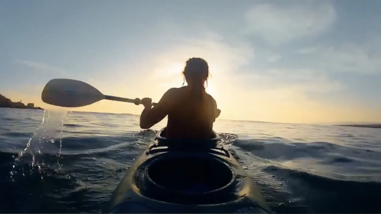 El sueño (2020) movie still: medium — A person in a kayak paddles across the open ocean during the golden hour. The low sun creates a silhouette of…