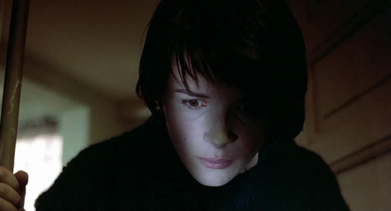Three Colours: Blue (1993) movie still: closeup — A dimly lit indoor space with blurred architectural shapes in the background. A young woman looks…