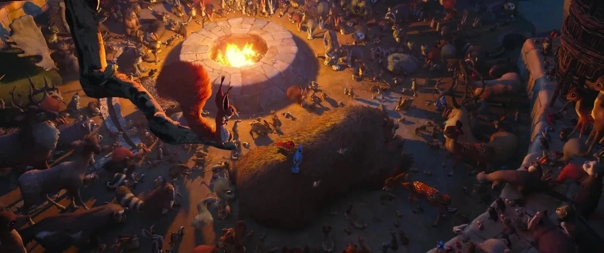 The Wild Robot (2024) movie still: wide — A dense crowd of stylized animals surrounds a stone fire pit in a dark clearing. The animals are perched…