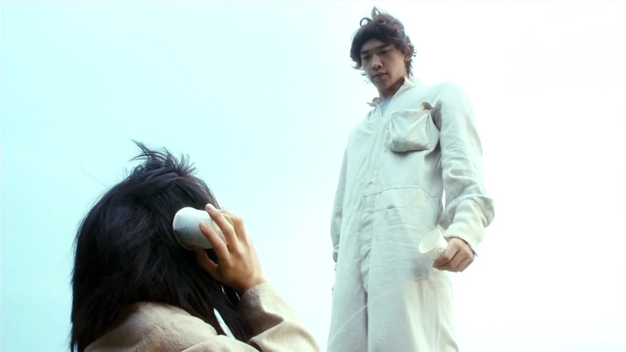I’m A Cyborg, But That’s Okay (2006) movie still: medium — An open, bright, featureless expanse with a sky-white background. A man stands while a…