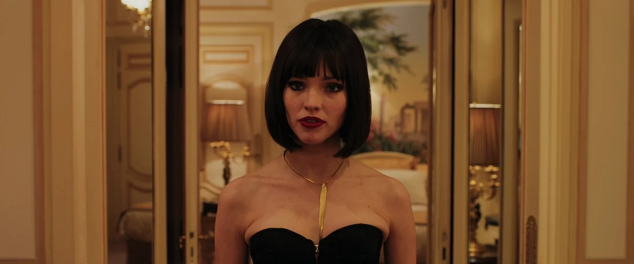 Anna (2019) movie still: medium — An upscale hotel suite features cream-colored walls and mirrors flanking a central doorway. A woman with dark hair…