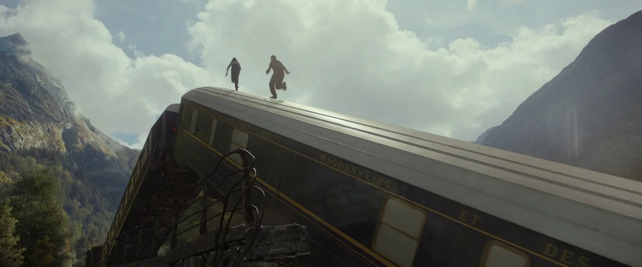 Mission: Impossible – Dead Reckoning Part One (2023) movie still: wide — A dark green passenger train car lies derailed and tilted at a steep angle.…