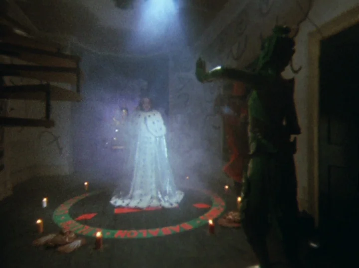 Lucifer Rising (1972) movie still: fullbody — A dark, smoke-filled room features a painted circle on the floor with red candles. A woman in a white…