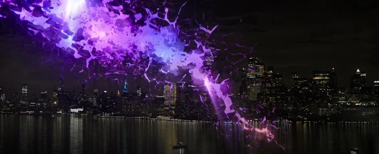 Spider-Man: No Way Home (2021) movie still: wide — A night view across a body of water toward a densely lit urban skyline. A jagged tear in space…