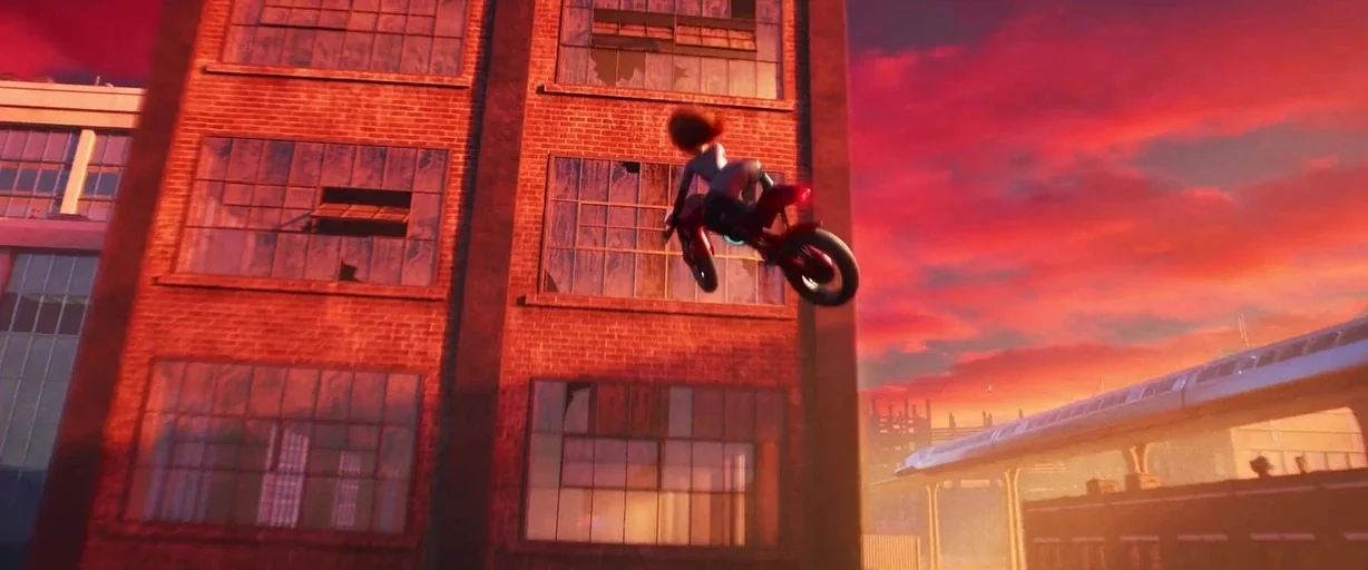 Incredibles 2 (2018) movie still: wide — A multi-story red brick industrial building features grid-patterned windows at sunset. A character rides a…