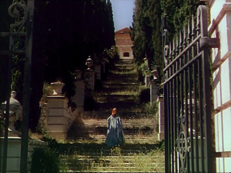 The Red Shoes (1948) movie still: wide — A long stone stairway framed by towering cypress trees leads toward a distant hilltop building. A lone…
