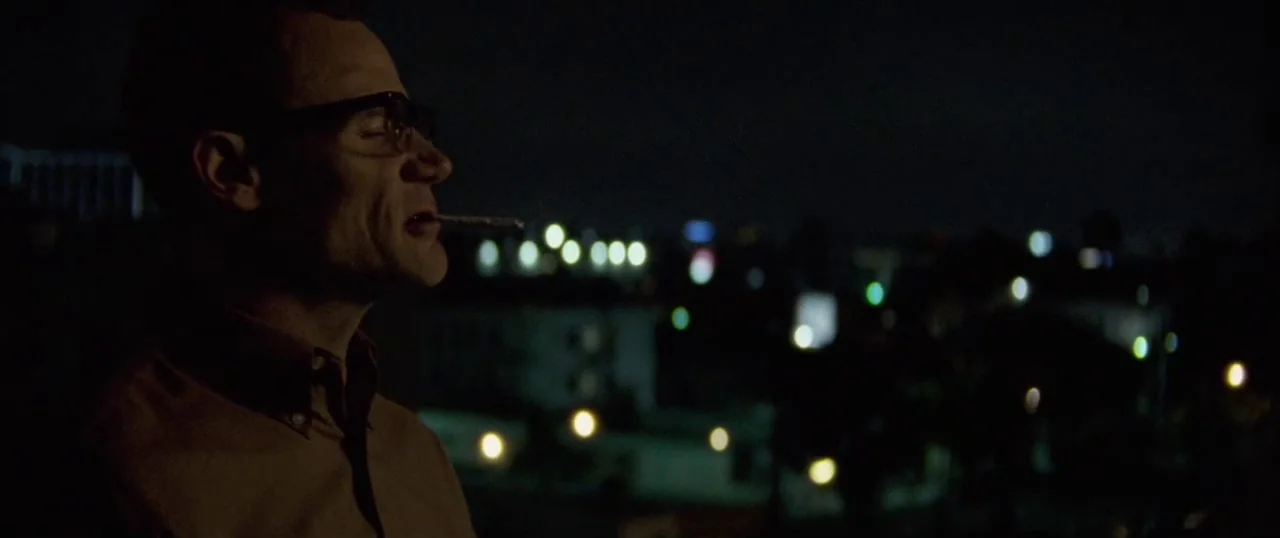 Low Down (2014) movie still: medium — A nighttime view from a rooftop overlooking a distant, blurred city skyline. A man stands in the foreground…