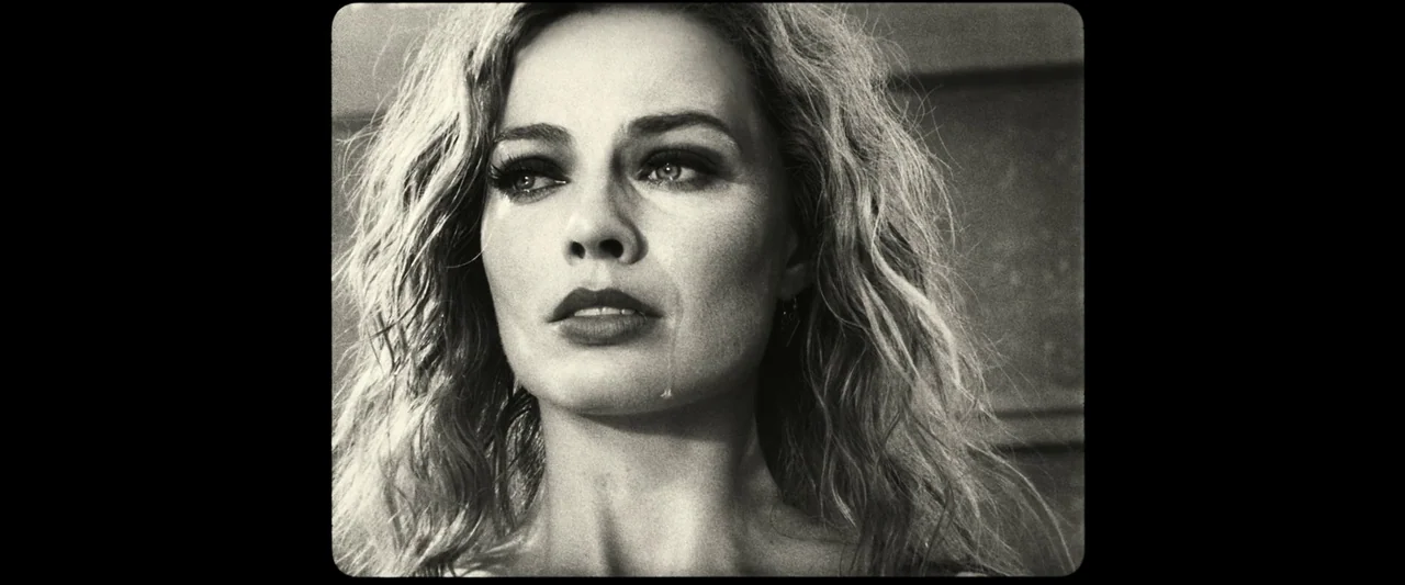 Babylon (2022) movie still: closeup — A close-up shot showing a woman against an abstract blurred background. She looks off-camera while a single…