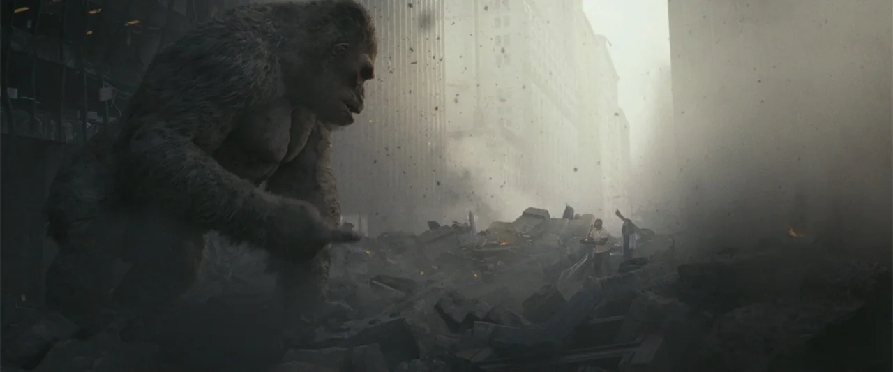 Rampage (2018) movie still: wide — A destroyed urban canyon filled with thick dust and heavy concrete debris. A giant ape looms in the foreground…