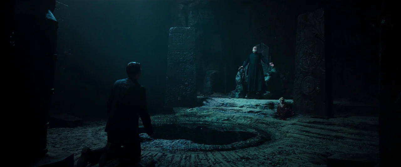 The Pope’s Exorcist (2023) movie still: wide — An underground chamber features stone floor engravings and monoliths etched with occult symbols. An…