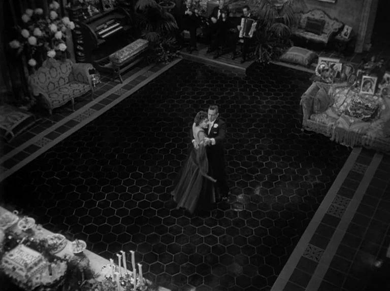 Sunset Boulevard (1950) movie still: wide — A spacious room features a dark hexagonal tiled floor and ornate classical furniture pieces. A man and…