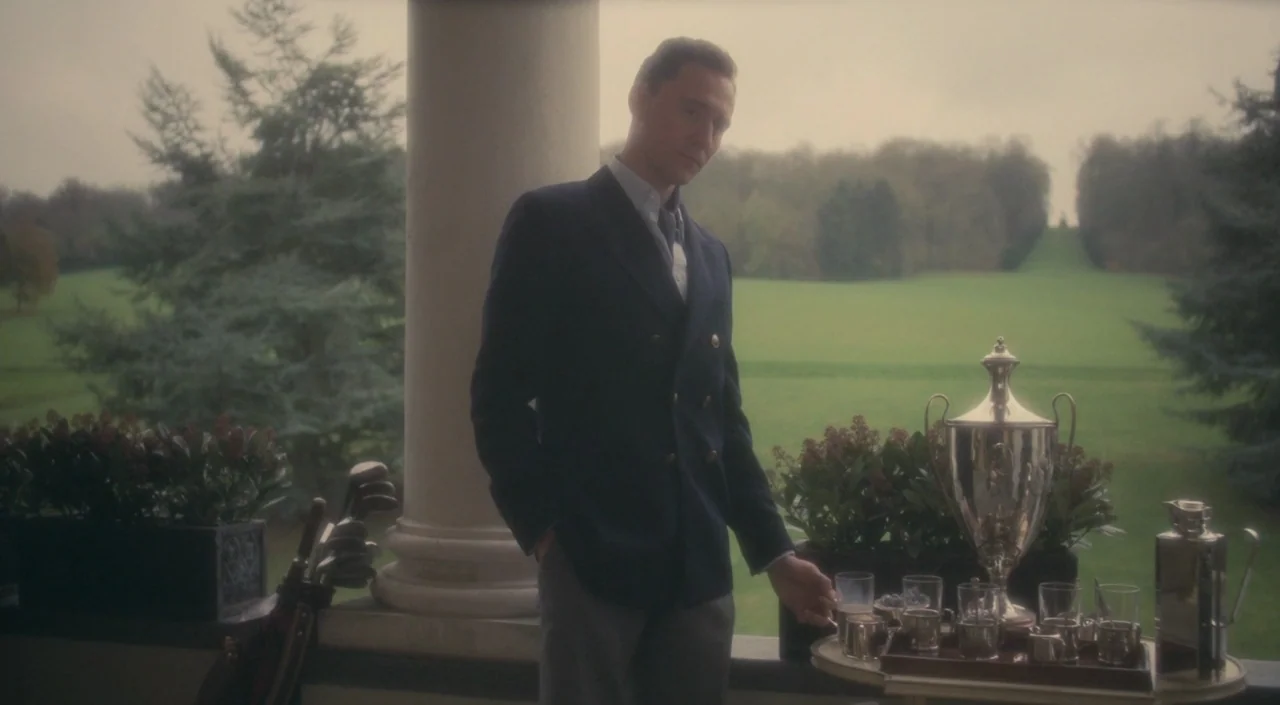 The Deep Blue Sea (2011) movie still: medium — An outdoor veranda overlooks a vast, verdant lawn under an overcast, gray sky. A man in a blazer…