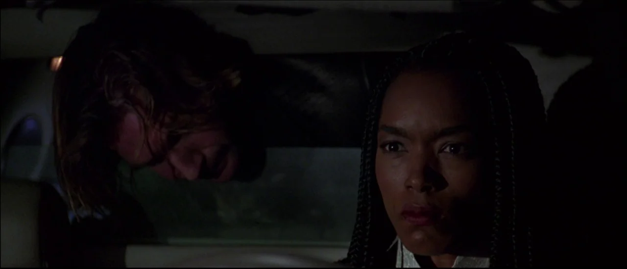 Strange Days (1995) movie still: medium — The interior of a moving vehicle at night with dark windows and sparse lighting. A woman looks straight…