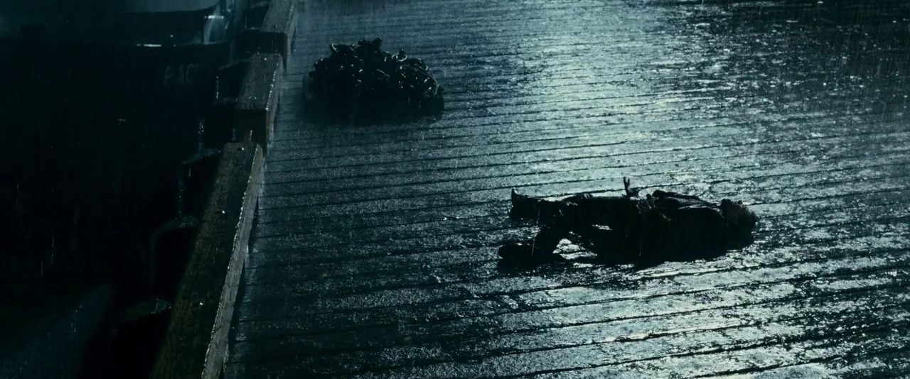 The Twilight Saga: Eclipse (2010) movie still: wide — A dark wooden pier at night is slick with heavy rain and reflections. A lone figure lies face…
