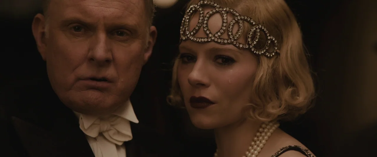 Live By Night (2016) movie still: medium — An opulent 1920s ballroom interior with dimly lit surroundings and dark decor. A man in a tuxedo stands…