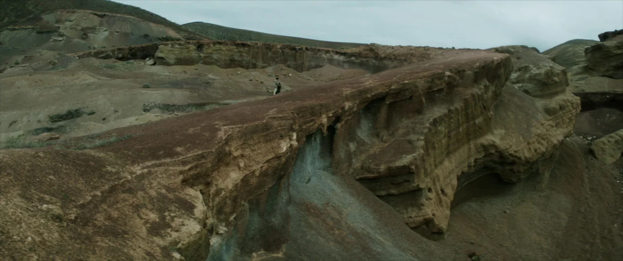 The Man Who Killed Don Quixote (2018) movie still: wide — An arid desert landscape features layered rock formations and dry, barren hills. The sky…