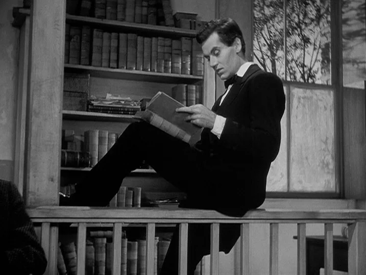 Young Mr. Lincoln (1939) movie still: medium — A dimly lit room contains wooden shelves filled with many old leather-bound books. A man in formal…