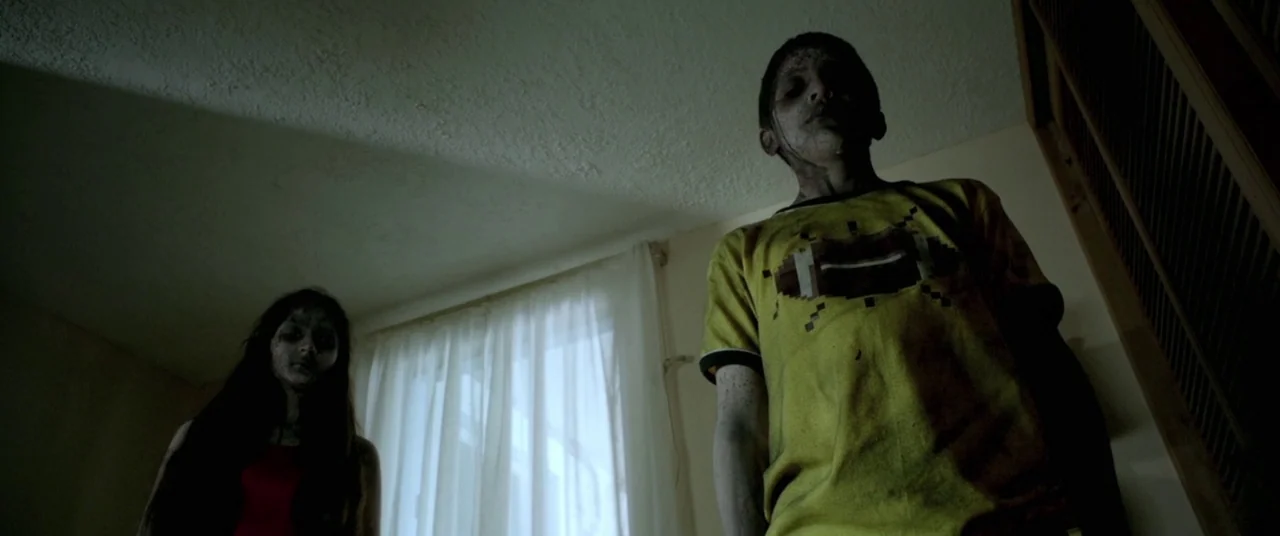 Here Comes The Devil (2012) movie still: medium — A dimly lit room with plain walls features a window covered by thin curtains. Two pale children…
