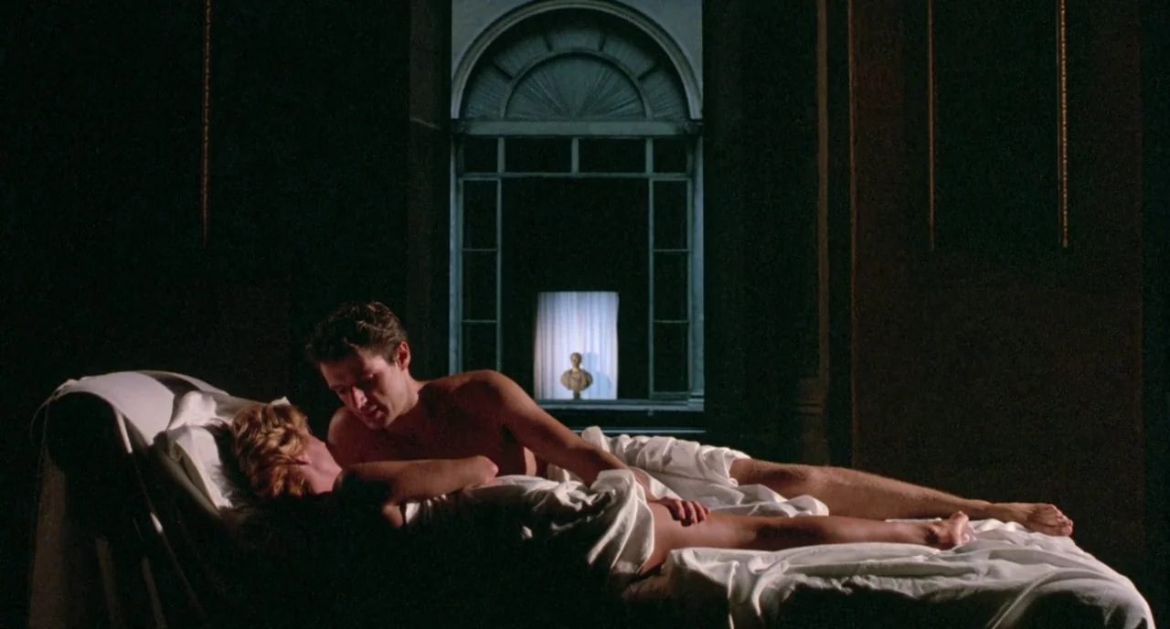 The Belly of an Architect (1987) movie still: medium — A dark, classical room features an arched doorway looking out onto a distant illuminated…