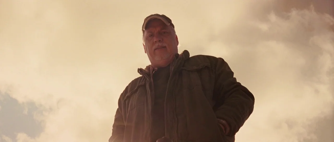Thor (2011) movie still: medium — An open outdoor space under a bright, cloudy sky provides the backdrop. A middle-aged man looks directly down…