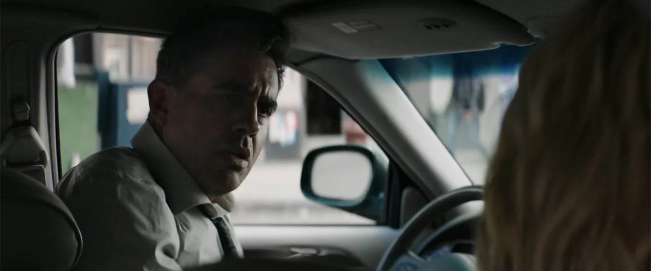 Jolt (2021) movie still: medium — The interior of a passenger car shows a man seated in the driver's position. He is turned toward the passenger,…