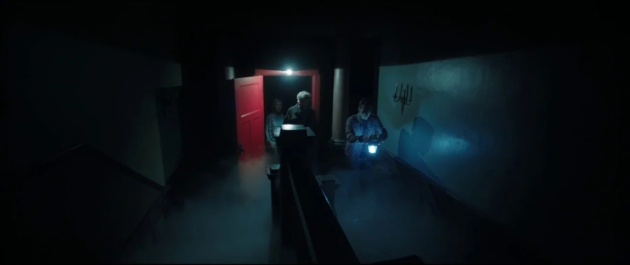 Insidious: Chapter 2 (2013) movie still: wide — A dark staircase is filled with thick ground fog and illuminated by a lantern. Three people ascend…