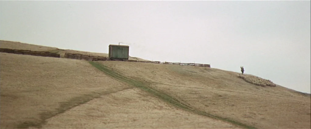 Far from the Madding Crowd (1967) movie still: wide — A vast, rolling, barren hillside under an overcast sky featuring a small wooden shack. A lone…