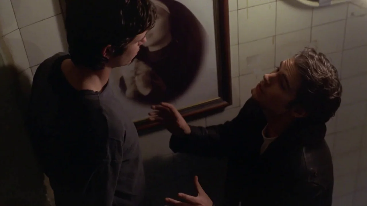 Hellraiser: Hellworld (2005) movie still: medium — A narrow stairwell features white-tiled walls adorned with a large framed artwork. One man…